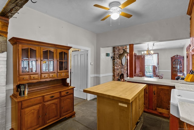 kitchen featuring hanging light fixtures, butcher block countertops, kitchen peninsula, a textured ceiling, and ceiling fan with notable chandelier