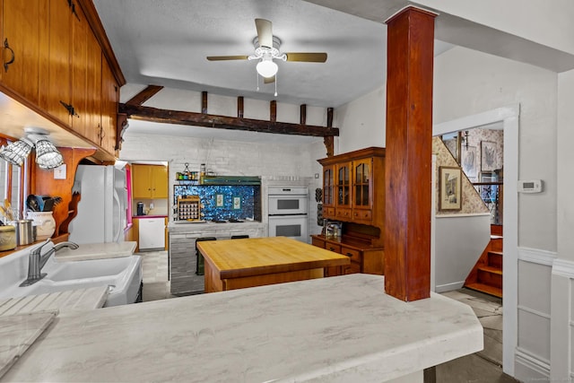 living room featuring a textured ceiling, ceiling fan, lofted ceiling with beams, and sink