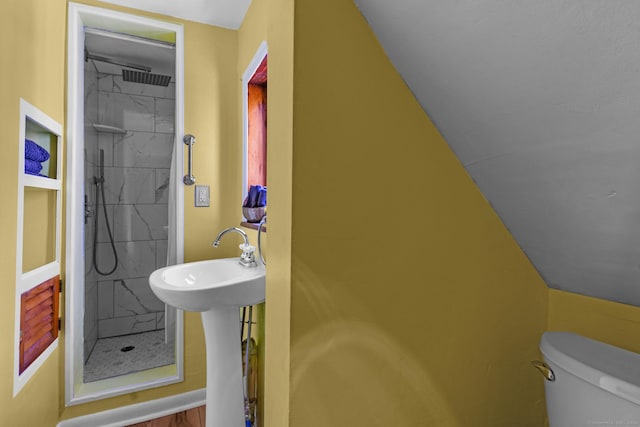 bathroom featuring sink, tiled shower, hardwood / wood-style flooring, toilet, and lofted ceiling