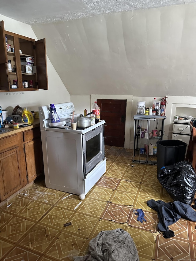 kitchen with light tile patterned flooring, stove, a textured ceiling, and vaulted ceiling