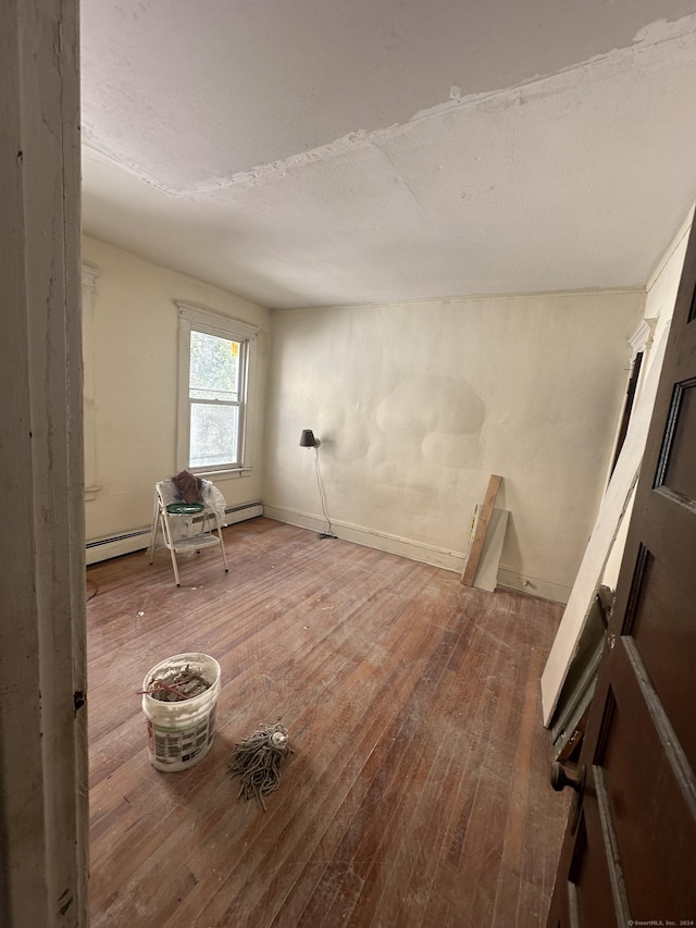 spare room featuring baseboard heating and hardwood / wood-style flooring