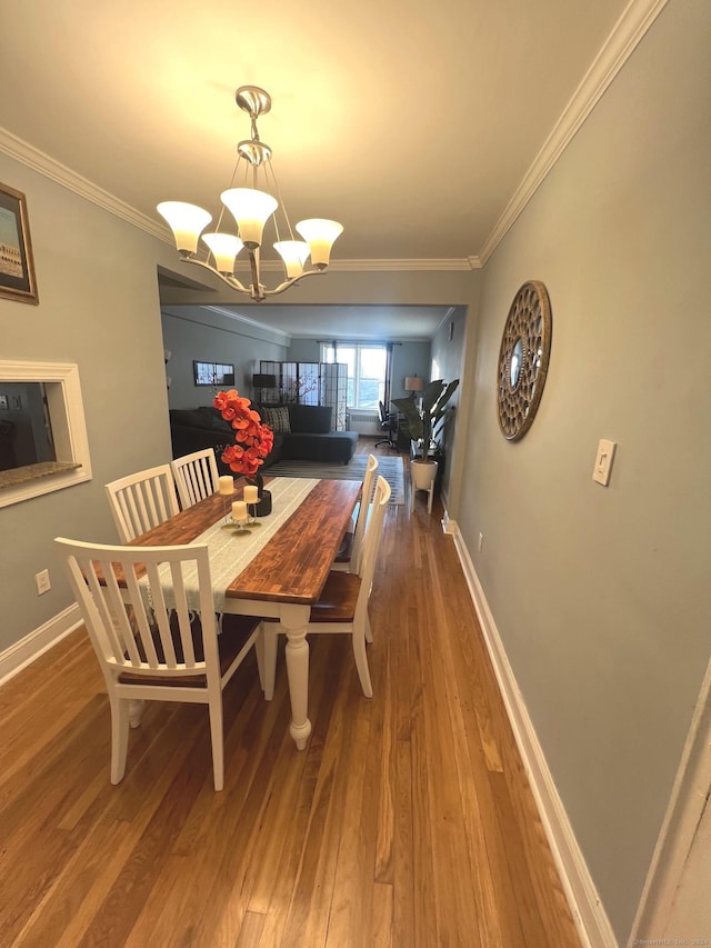 dining area with crown molding, hardwood / wood-style floors, and an inviting chandelier