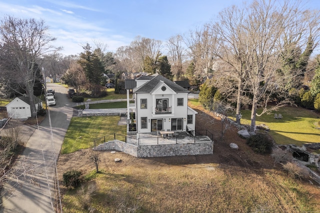 back of house with a balcony and a yard