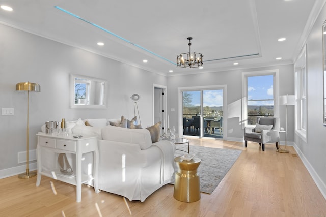 living room featuring light wood-type flooring, crown molding, and a notable chandelier