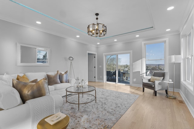 living room featuring a chandelier, ornamental molding, and light hardwood / wood-style flooring