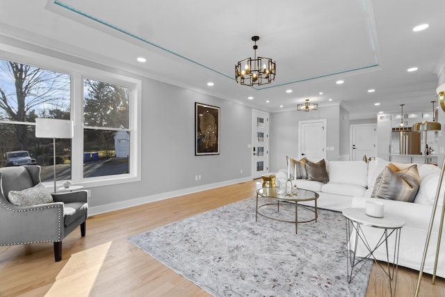 living room featuring light hardwood / wood-style flooring, ornamental molding, and a notable chandelier