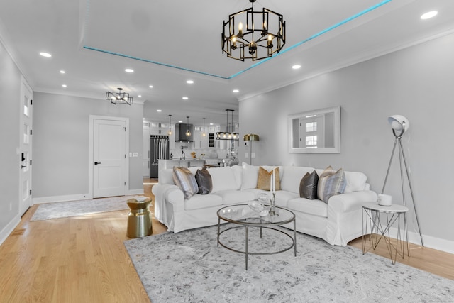 living room featuring an inviting chandelier, crown molding, and light hardwood / wood-style flooring