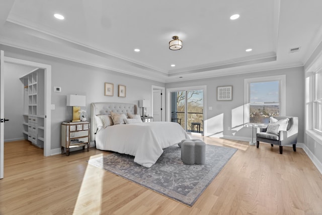 bedroom with a raised ceiling, access to exterior, crown molding, and light hardwood / wood-style flooring