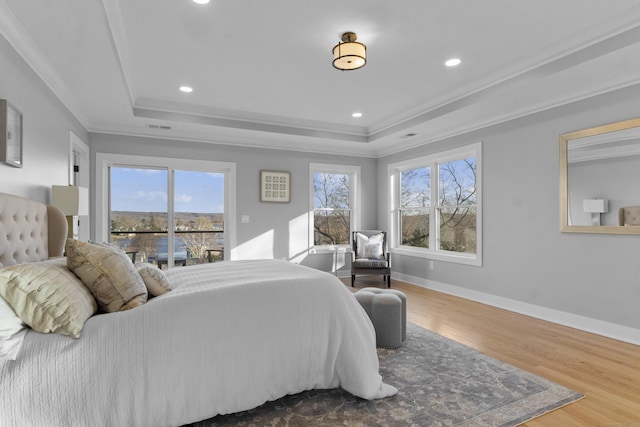 bedroom featuring hardwood / wood-style floors, a raised ceiling, and ornamental molding