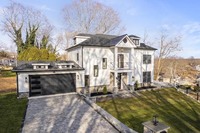 view of front of home with a garage, a balcony, and a front lawn