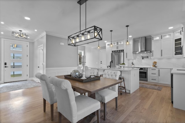 dining room with light wood-type flooring and crown molding