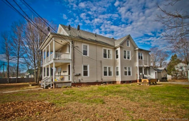 rear view of house featuring a balcony and a yard