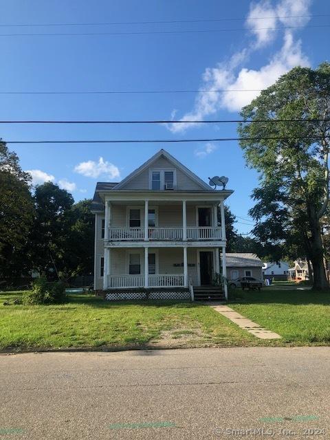 neoclassical home featuring a front lawn