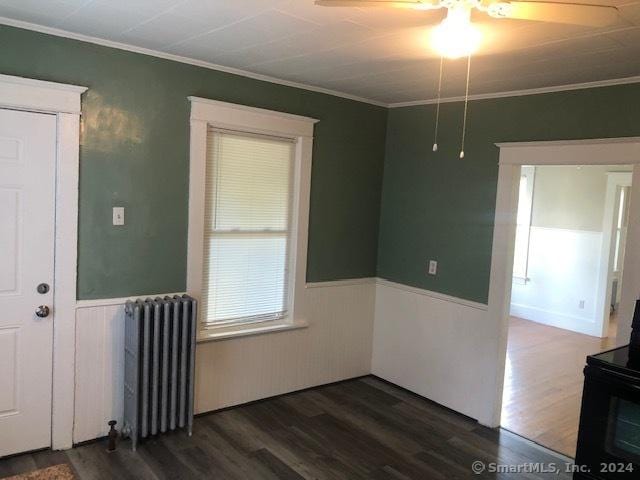 spare room featuring dark hardwood / wood-style floors, ceiling fan, crown molding, and radiator