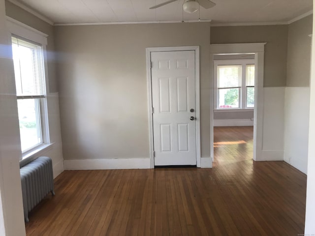 spare room with ceiling fan, radiator heating unit, dark wood-type flooring, and a wealth of natural light