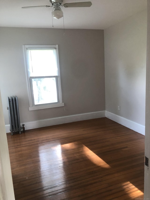 spare room with ceiling fan, dark wood-type flooring, and radiator