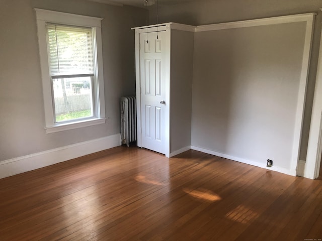 unfurnished room featuring plenty of natural light, dark wood-type flooring, and radiator