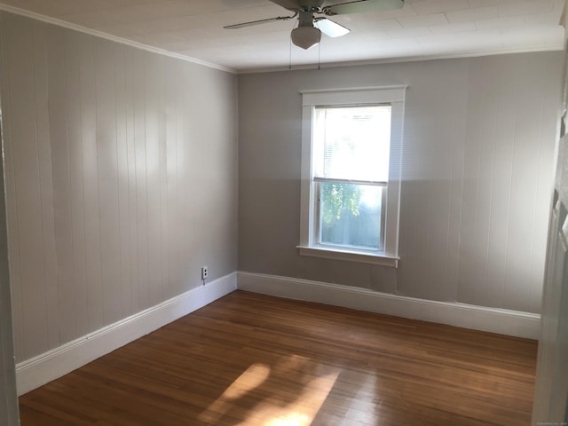 empty room with ornamental molding, ceiling fan, dark wood-type flooring, and wood walls