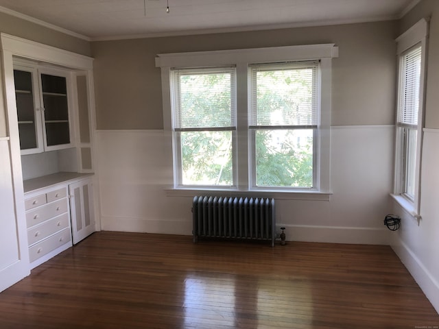 interior space with radiator heating unit, dark wood-type flooring, and ornamental molding