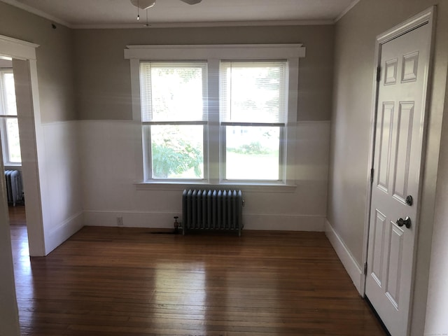 unfurnished room with dark hardwood / wood-style floors, ceiling fan, crown molding, and radiator