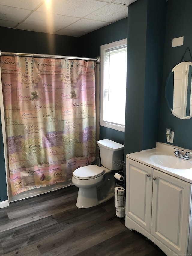 bathroom featuring a drop ceiling, vanity, a shower with shower curtain, toilet, and wood-type flooring