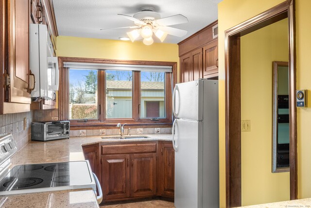 kitchen with white appliances, sink, ceiling fan, a textured ceiling, and tasteful backsplash