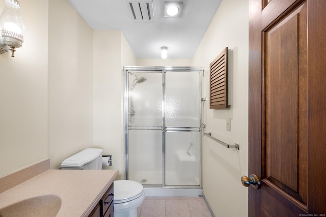 bathroom with tile patterned flooring, vanity, toilet, and a shower with door