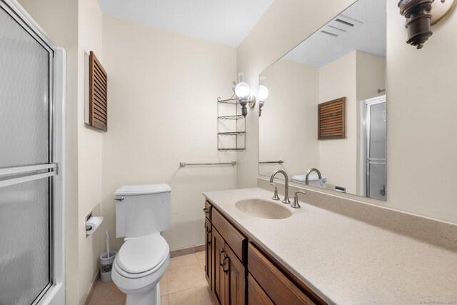 bathroom featuring tile patterned floors, vanity, toilet, and walk in shower