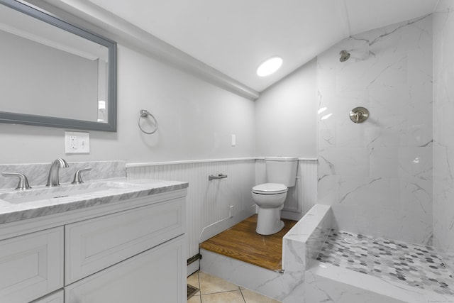 bathroom featuring vanity, toilet, tiled shower, and vaulted ceiling