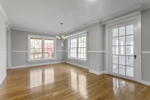 unfurnished dining area with crown molding, a notable chandelier, and light wood-type flooring