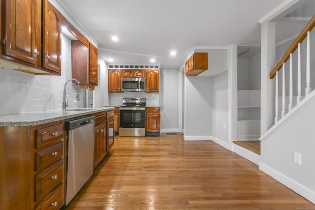 kitchen with backsplash, stainless steel appliances, light hardwood / wood-style flooring, and sink