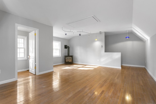 unfurnished living room featuring a wood stove, hardwood / wood-style flooring, and vaulted ceiling