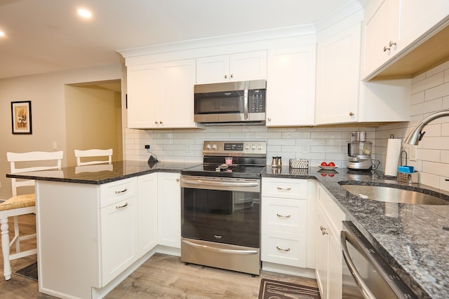 kitchen with white cabinets, a kitchen breakfast bar, sink, appliances with stainless steel finishes, and kitchen peninsula