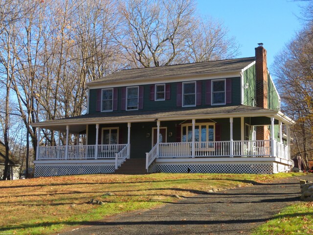 farmhouse-style home featuring covered porch and a front yard