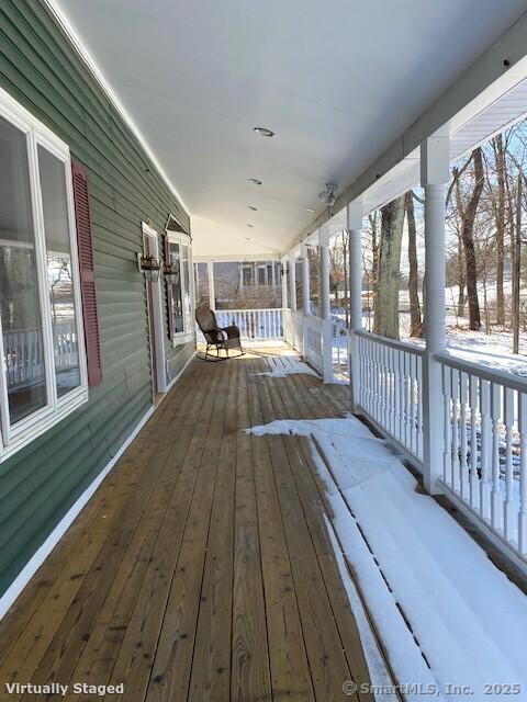 snow covered deck featuring covered porch