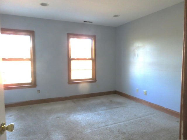 spare room featuring carpet, baseboards, and a wealth of natural light