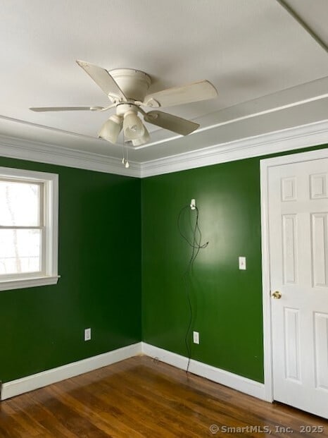 spare room with ceiling fan, dark wood-type flooring, baseboards, and ornamental molding