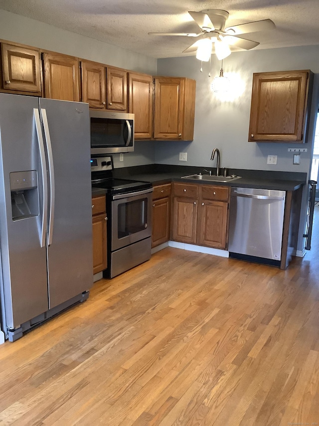 kitchen featuring sink, ceiling fan, light wood-type flooring, a textured ceiling, and stainless steel appliances