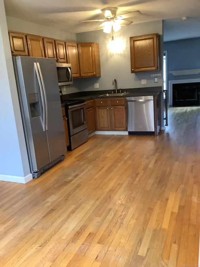 kitchen with ceiling fan, sink, light wood-type flooring, and stainless steel appliances