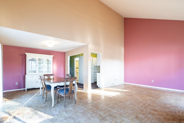 dining area featuring light parquet floors and high vaulted ceiling