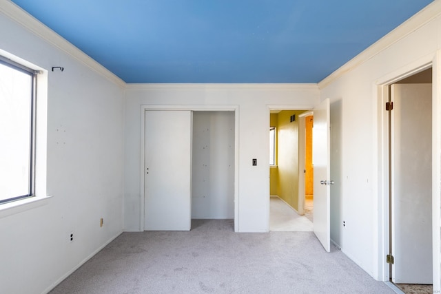 unfurnished bedroom with light colored carpet, crown molding, and a closet