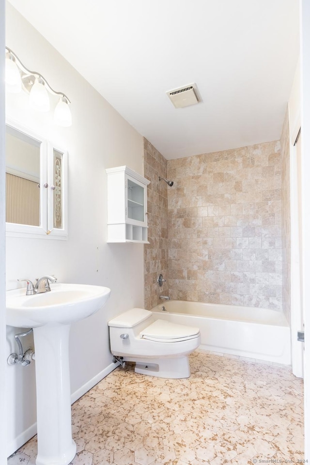 bathroom featuring toilet and tiled shower / bath