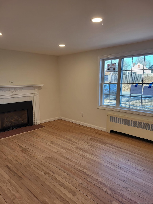 unfurnished living room featuring radiator and light wood-type flooring