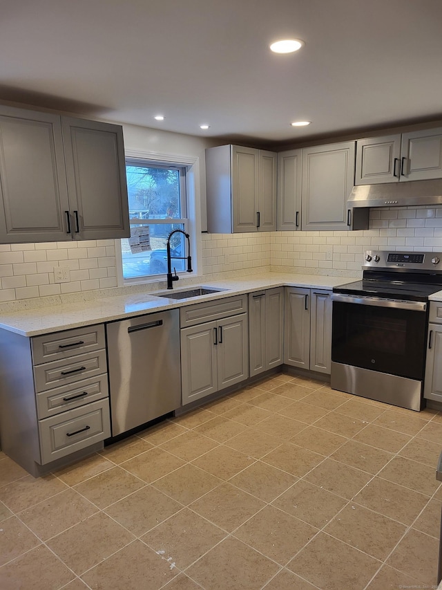 kitchen with tasteful backsplash, appliances with stainless steel finishes, gray cabinets, and sink