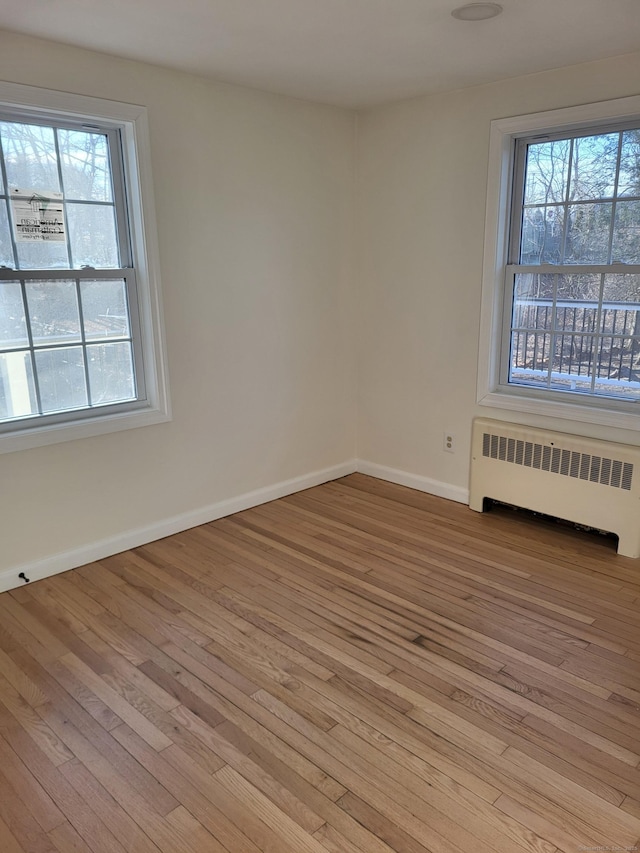 unfurnished room with radiator heating unit and light hardwood / wood-style floors