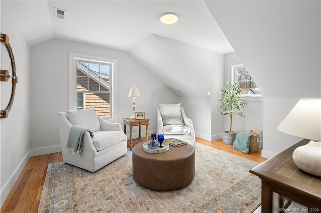 sitting room with a wealth of natural light, wood-type flooring, and vaulted ceiling