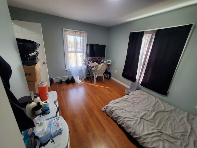 bedroom with hardwood / wood-style floors and baseboard heating