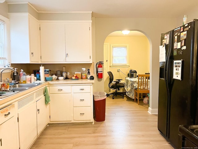 24 Brewster St, Stratford, CT 06614 - kitchen featuring black fridge, light countertops, arched walkways, light wood finished floors, and white cabinetry