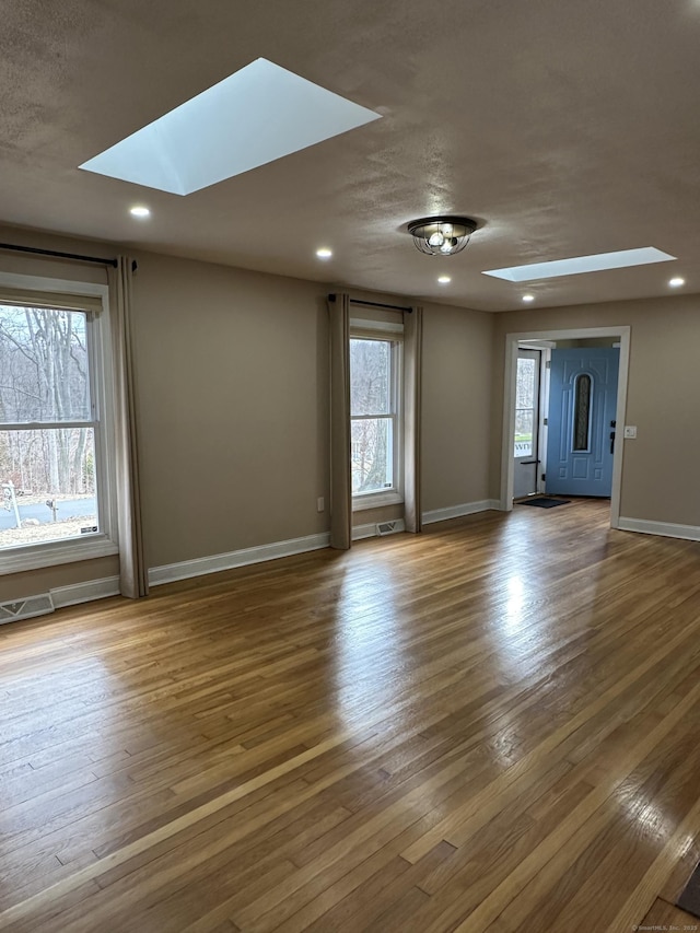 spare room with hardwood / wood-style floors and a skylight