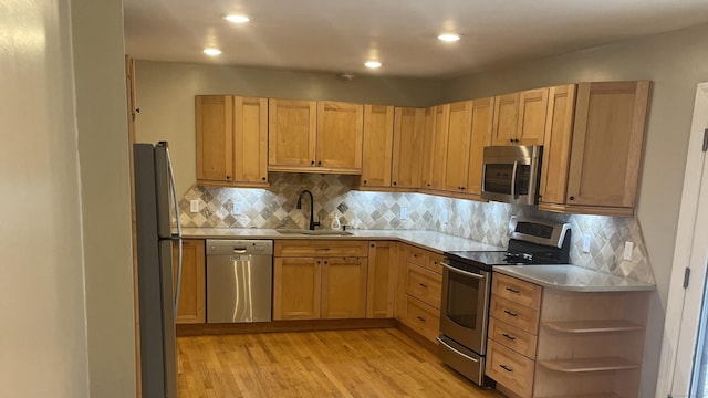 kitchen with sink, light brown cabinets, stainless steel appliances, tasteful backsplash, and light hardwood / wood-style floors